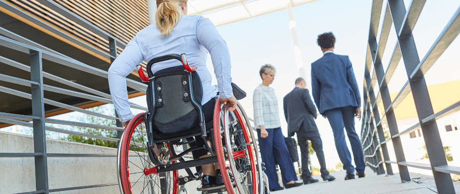 Image of woman in wheelchair following group of men on walkway